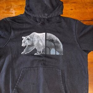 Black and gray North face hoodie with a bear logo on the front